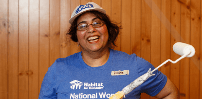 woman smiling, holding a paint roller