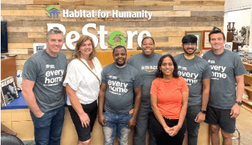 group of people in front of a Habitat for Humanity ReStore sign and desk