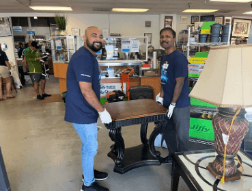 two men smiling and lifting a table at the ReStore