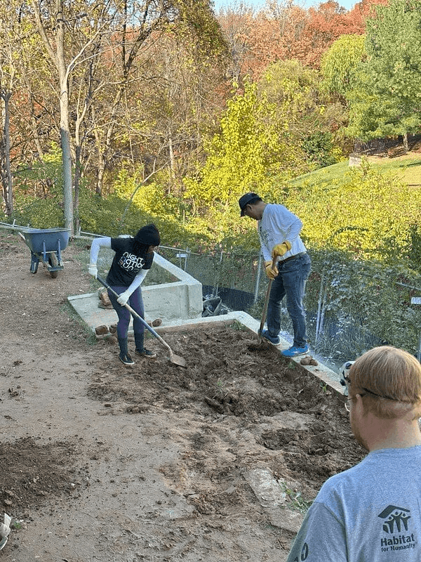 three people with shovels digging dirt in garden/yard