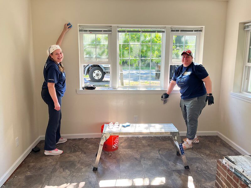 two people wiping new windows and walls, smiling 