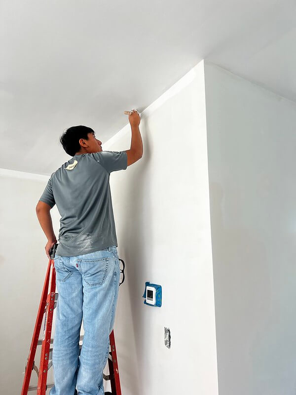 person on ladder painting ceiling